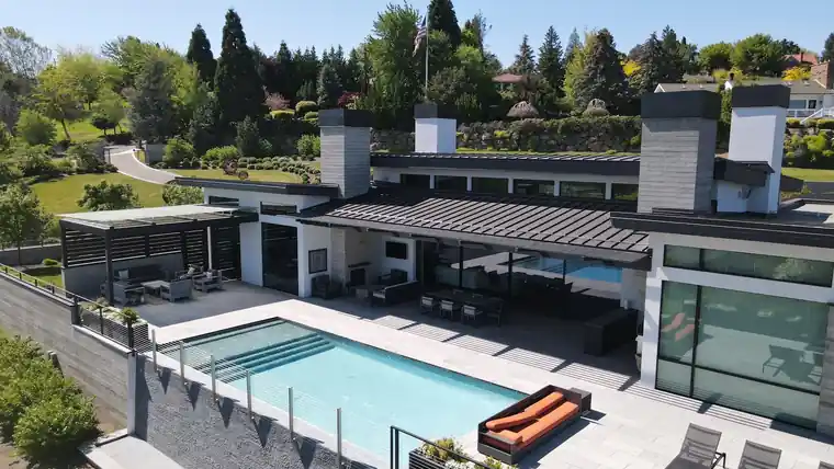 Aerial view of a modern house with a pool under a dark standing-seam metal roof