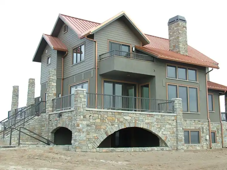 Copper standing-seam roof on a stone and sage-green house