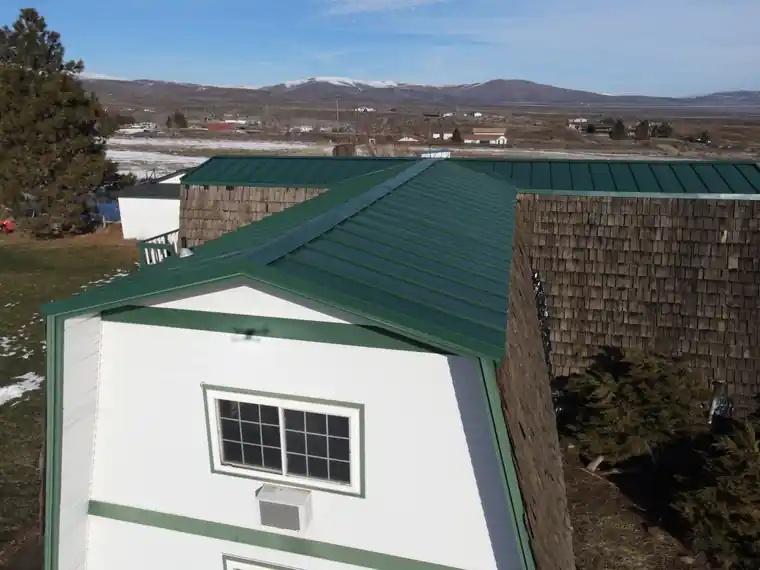 Green metal roof over cedar shake walls with snow on the ground