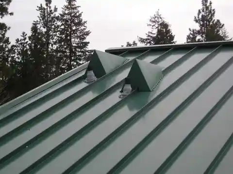 Green metal roof with roof vents on a home
