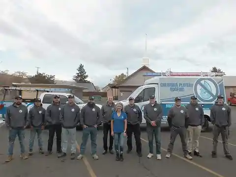 The Columbia Plateau crew in company hoodies beside the company van, with a church behind them