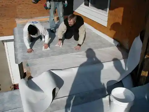 Two crew members laying roofing membrane